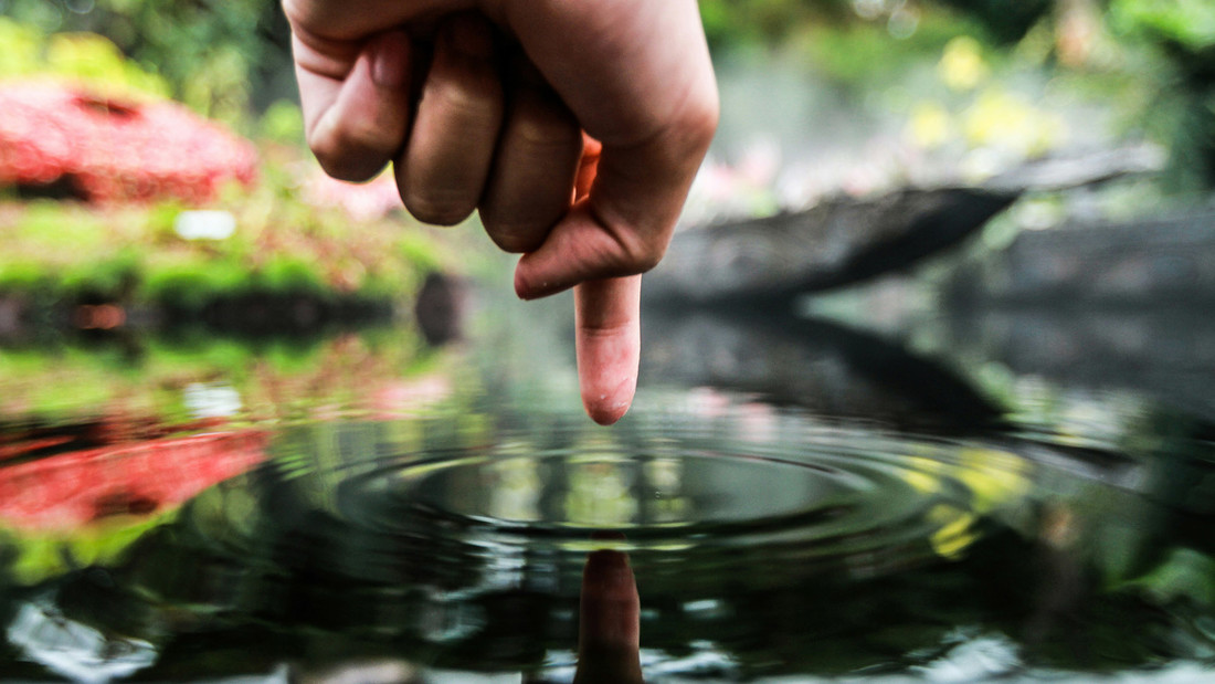 Hand berührt Wasseroberfläche