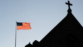 Am Himmel weht eine amerikanische Flagge und daneben ist die Silhouette einer Kirche zu erkennen.