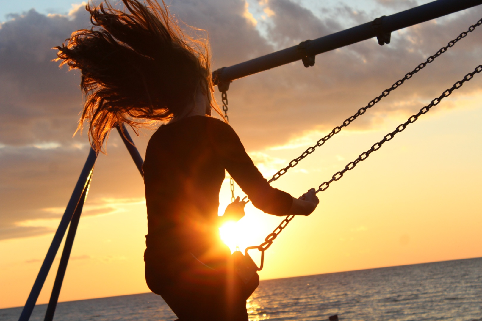 Frau schaukelt im Sonnenuntergang