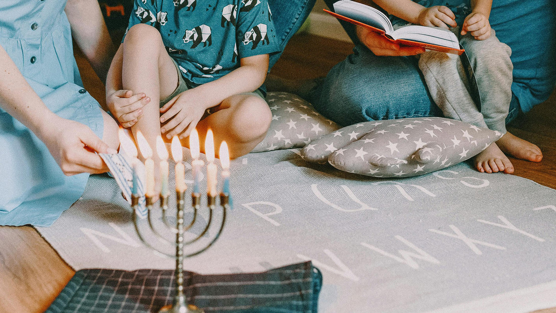 Familie mit Chanukka-Kerzenständer und Buch in der Hand