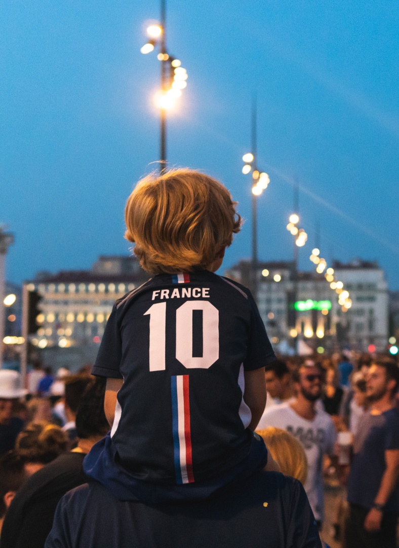 Junge im Trikot auf den Schultern seines Vaters