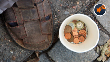 Becher mit Münzen neben einem Schuh