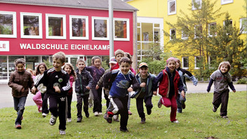 Schüler laufen lachend vor Grundschule