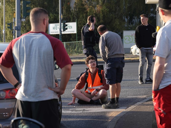 Ein Autofahrer streitet mit einem Aktivisten der Gruppe "Letzte Generation", der zu den sieben Personen gehört, die sich auf den Asphalt geklebt haben, um eine Kreuzung an einer Ausfahrt der A100 zu blockieren