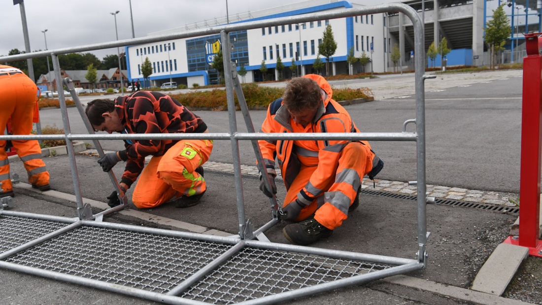 Arbeiter errichten Absperrgitter von dem Stadion Chemnitz. 