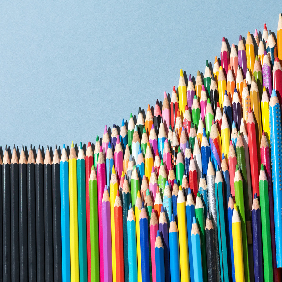 Viele Buntstifte sind der Größe nach geordnet und enden in immer kürzer werdenden schwarzen Stiften