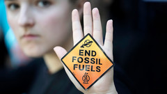 Demonstrantin zeigt ein Schild mit der Aufschrift "end fossil fuels" (Ende der fossilen Brennstoffe) auf dem UN-Klimagipfel COP28