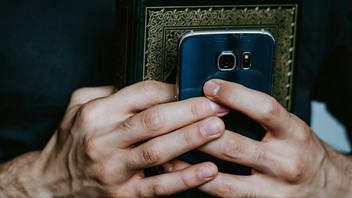 Hand mit Buch und Smartphone