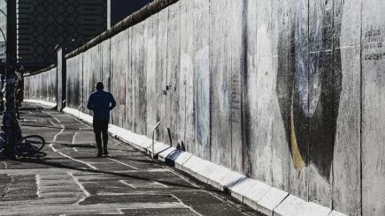 Mann läuft entlang der Berliner Mauer