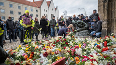 Menschen legen vor der Kirche Blumen ab