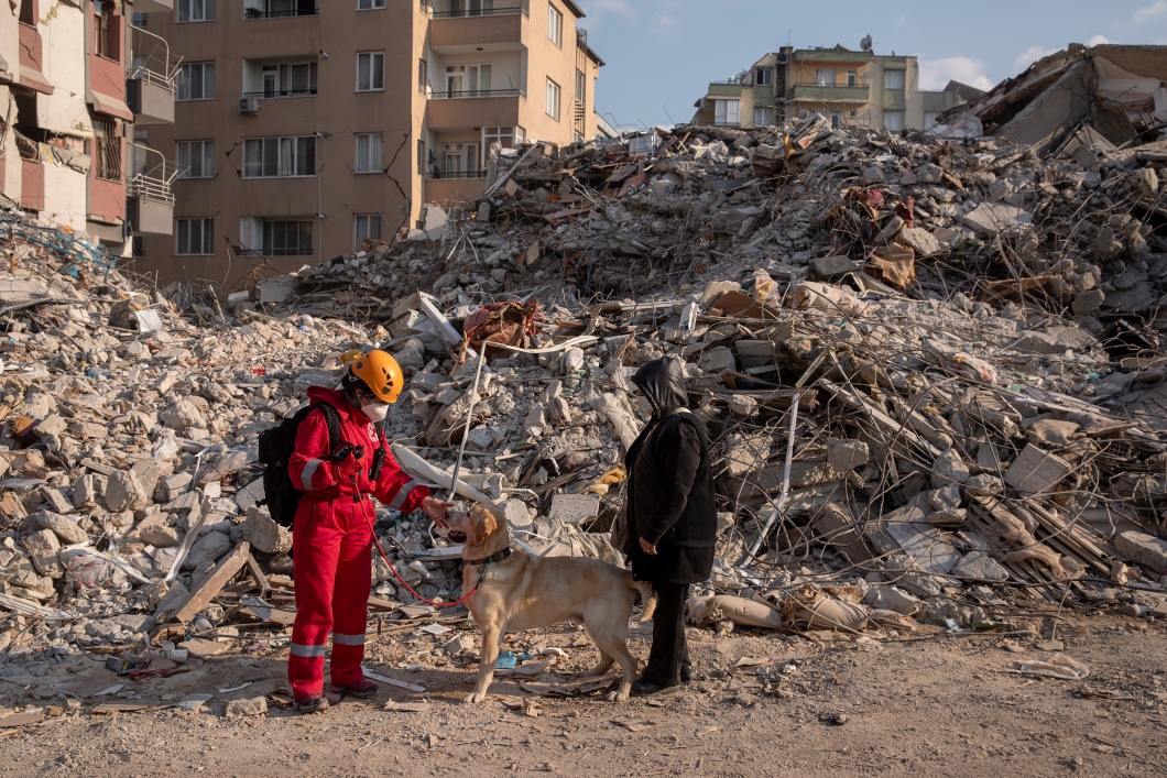Ein Helfer des Roten Kreuzes steht am 12. Februar mit einem Suchhund vor den Ruinen eines Gebäudes in Hatay.