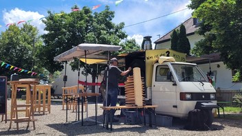 Mobiler Pizzaofen des Vereins "Mannanu", montiert auf einen Piaggio Ape, rundherum Stehtische und Stühle 