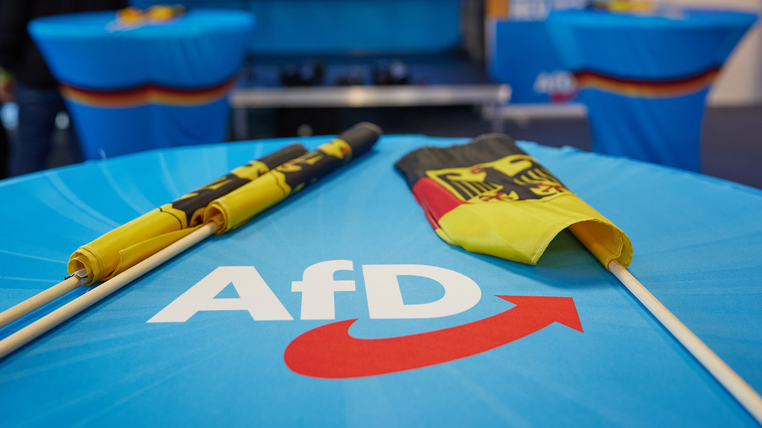 Deutschlandflaggen auf einem blauen Tisch mit AfD-Logo