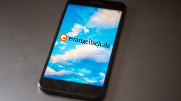 App von Bluesky ist auf einem Smartphone mit evangelisch.de Logo