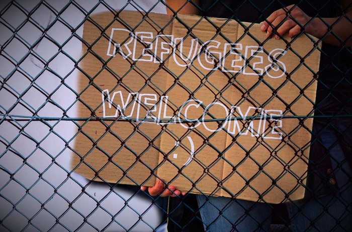 Schild mit Refugees Welcome hinter einem Zaun