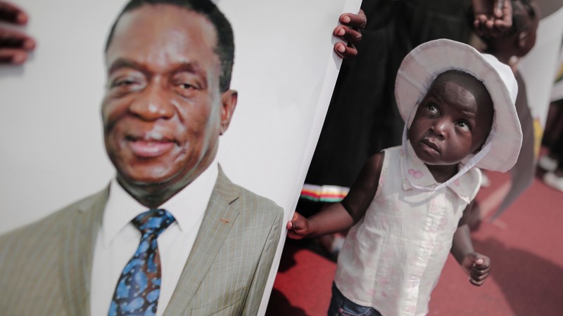 Ein kleines Mädchen blickt fragend auf das Foto des neuen Präsidenten Emmerson Mnangagwa