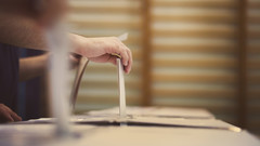 Hand wirft Wahlzettel in Wahlurne