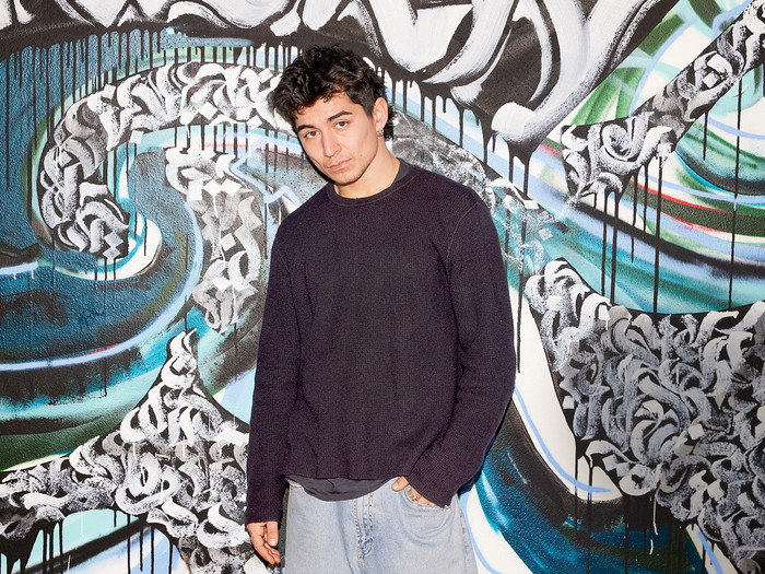 Serhat Perhat, 27, steht vor einer Wand, die mit Graffitis bemalt ist