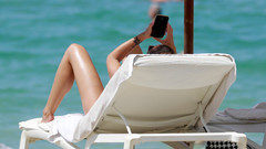 Eine Frau schaut auf ihr Handy am Strand