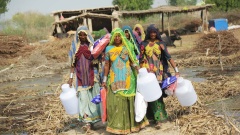 Im Dorf Ramji Kachi in der Provinz Sindh tragen Frauen Dinge wie Moskitonetze, Hygienesets aber auch Lebensmittel, die Helfer zuvor verteilt hatten