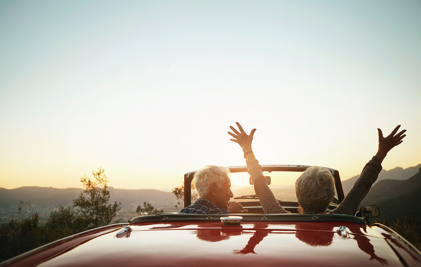 Ein Paar fährt im Cabrio der Sonne entgegen.