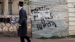 Ein orthodoxer Jude läuft an einem zerrissenen Plakat vorbei