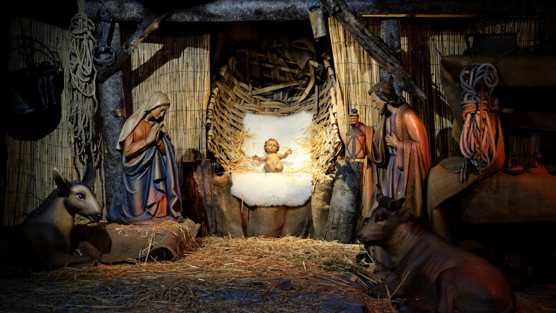 Ochse und Esel umrunden das Jesuskind und Maria und Josef in einer Krippe