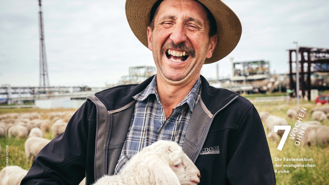 lachender Schäfer mit Schaf auf dem Arm