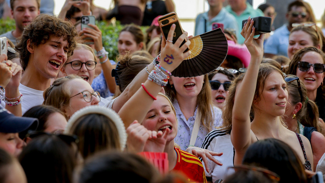 Junge Menschen stehen gedrängt mit gestreckten Armen und freuen sich auf ein Konzert.