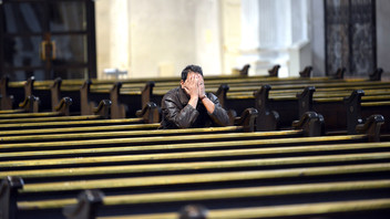 Mann sitzt in einer leeren Kirche und betet.