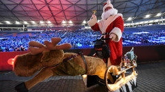 Stadionsingen auf der Westtribüne der stimmungsvoll beleuchteten Heinz von Heiden Arena am Maschsee mit Weihnachtsmann davor.