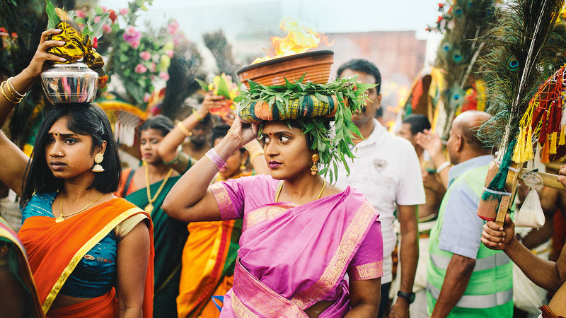 Beim Wagenfest "Theer" trägt eine junge Frau eine Feuerschale um den Tempel 