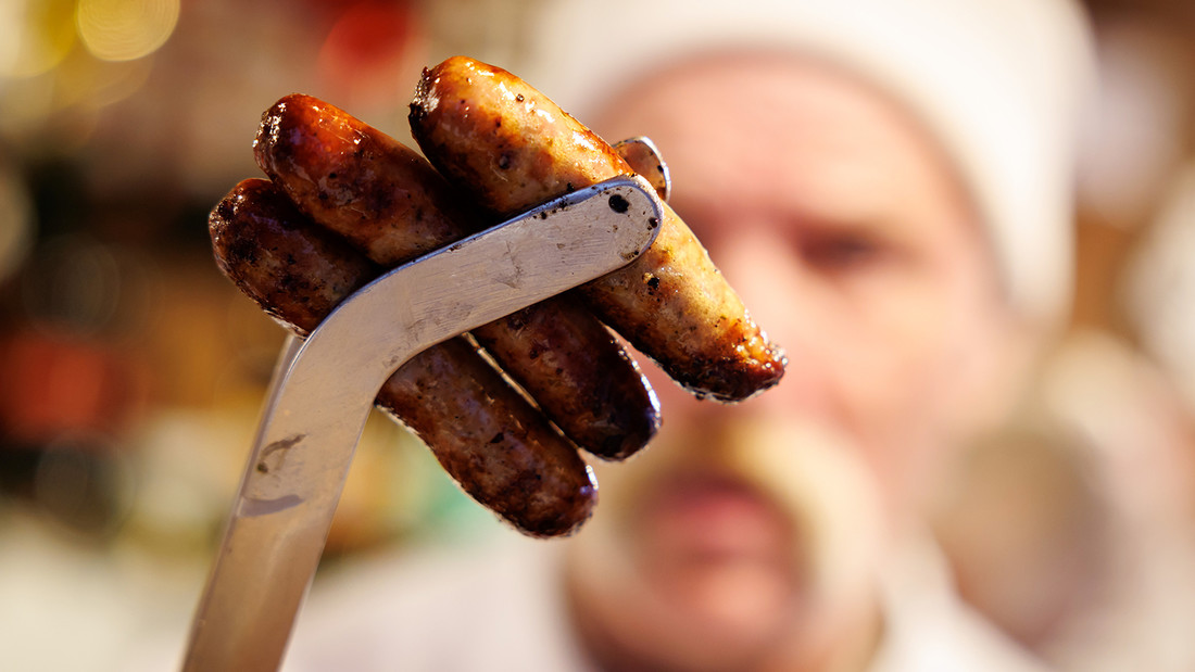 Nürnberger Bratwürste stecken auf dem Nürnberger Christkindlesmarkt in einer Grillzange. 