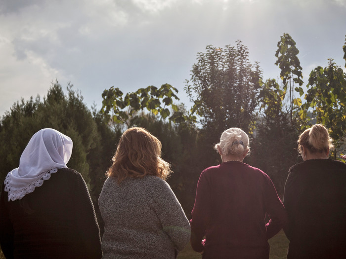 Klient:innen von Medica Gjakova in einem Garten mit Bäumen und Hühnern. Medica Gjakova ist die kosovarische Partnerorganisation der Frauenrechtsorganisation Medica Mondiale