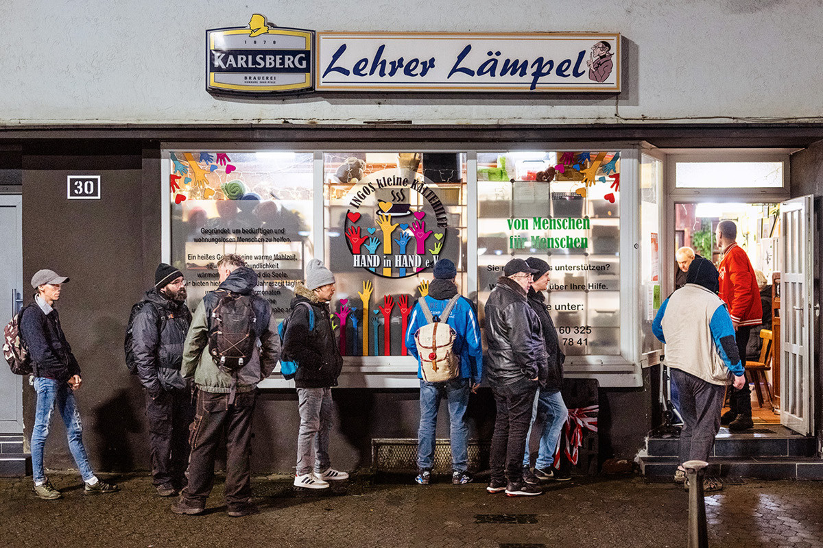 Menschen stehen auf dem Bürgersteig der Stengelstraße und warten vor einer Gaststätte, deren Reklame "Lehrer Lämpel" schon seit Jahren nicht mehr leuchtet