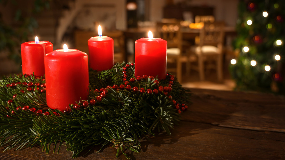Adventskranz mit vier Kerzen vor Weihnachtsbaum
