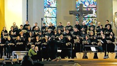 Ein Chor singt im Altarraum einer Kirche.