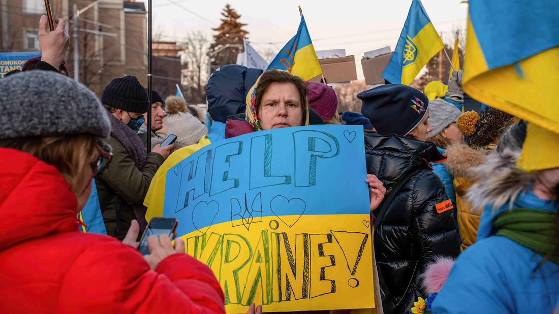 Eine Frau hält in einer Demo ein Schild mit der Aufschrift "Help Ukraine" hoch