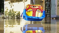 Kinderschaukel knapp über braunen Hochwasser