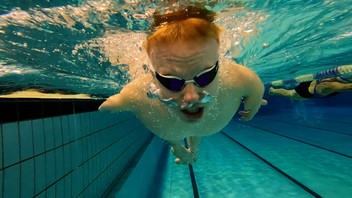 Ein junger Mann ohne Beine schwimmt unter Wasser