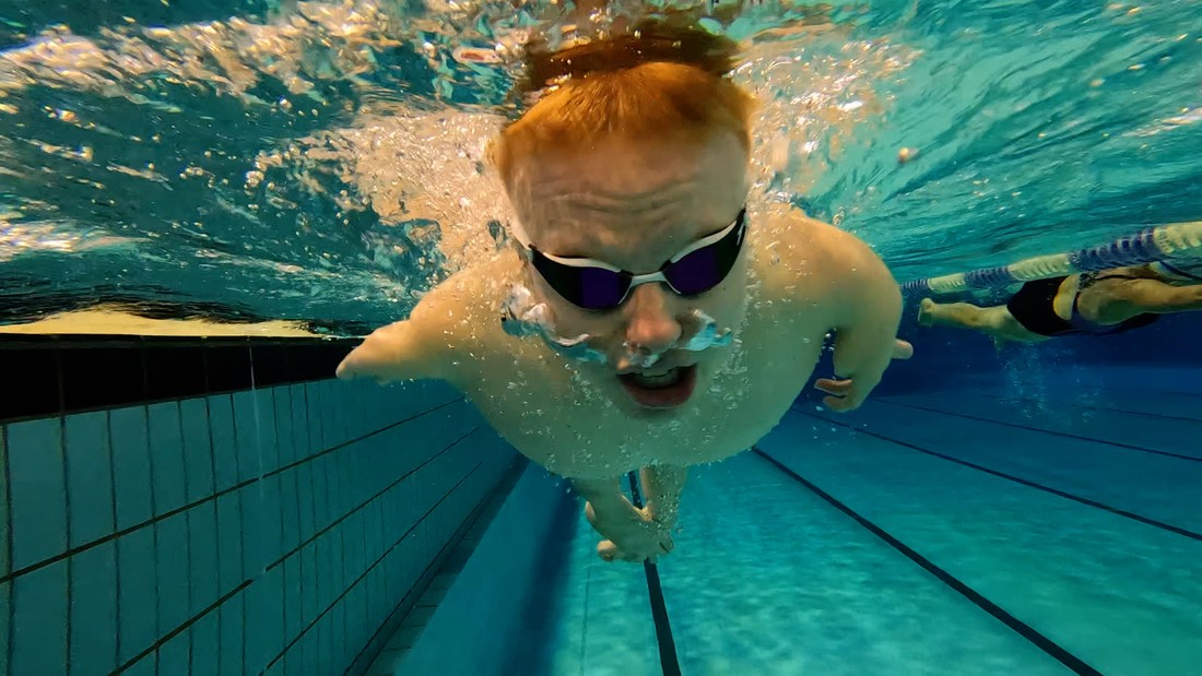 Ein junger Mann ohne Beine schwimmt unter Wasser