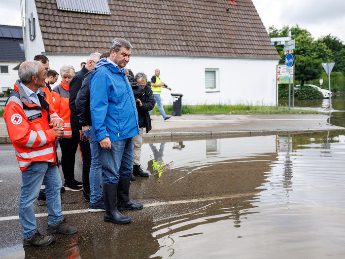 Markus Söder (CSU), Parteivorsitzender und Ministerpräsident von Bayern, verschafft sich einen Überblick zur Hochwasserlage an einer überfluteten Straße nahe der Donaubrücke