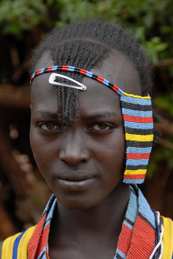 Portrait eines Mädchens mit einer traditionellen afrikanischen Frisur und buntem Kopfschmuck auf dem Markt von Keyafer Äthiopien 