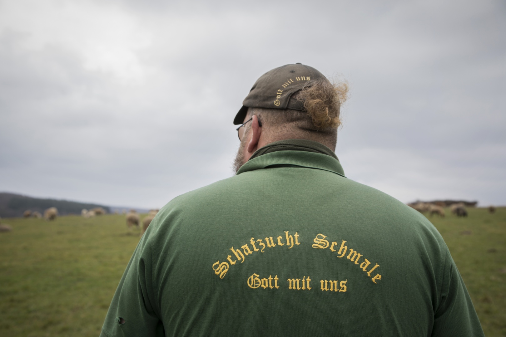 Hirte Thorsten Schmale von hinten mit Aufdruck auf Hemd "Schafzucht Schmale – Gott mit uns"