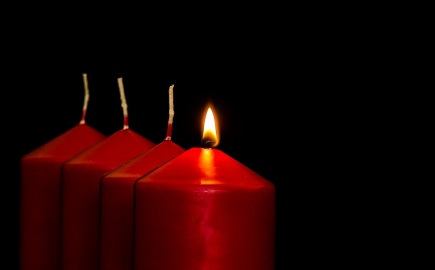 Eine von vier roten Kerzen brennt