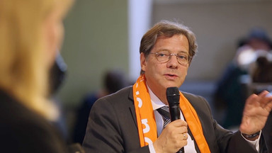 Portait von Markus Dröge mit orangen Schal und redent.