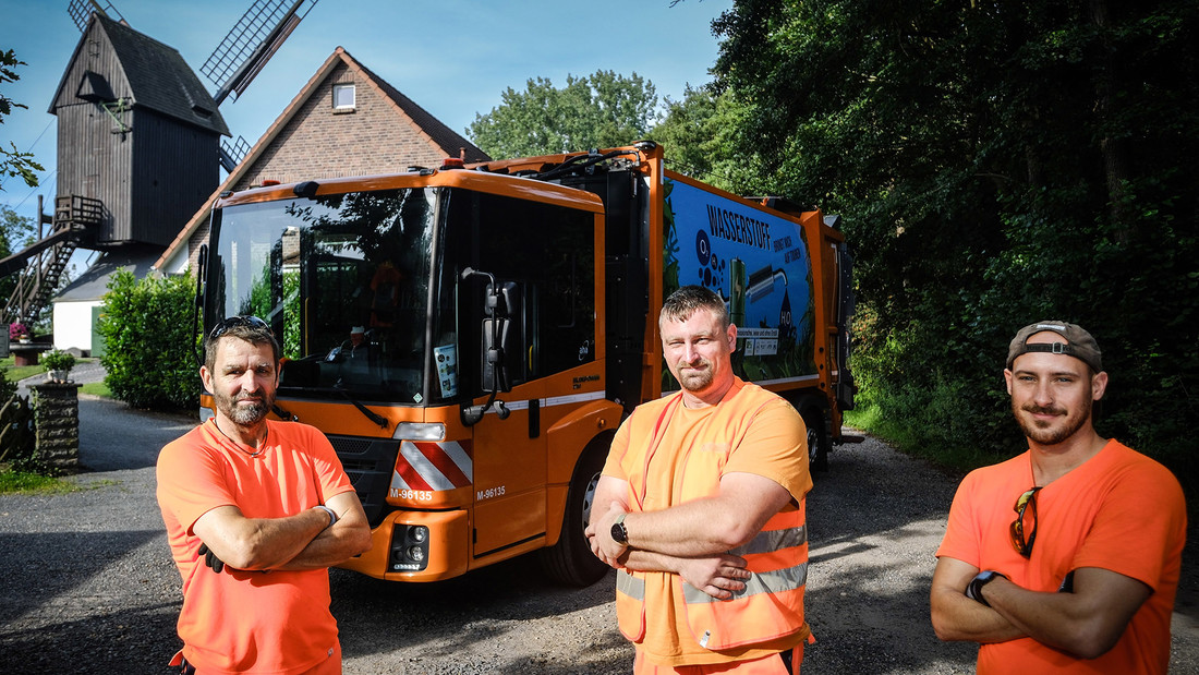 Portrait von drei Müllwerkern vor Wasserstoff betriebenem Fahrzeug