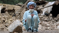 Mann sitzt vor zerstörtem Haus in der afghanisch-pakistanischen Grenzregion