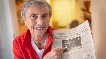 Annemarie Reffert hält eine Tageszeitung in der Hand, die über ihren Grenzuebergang 1989 informiert.