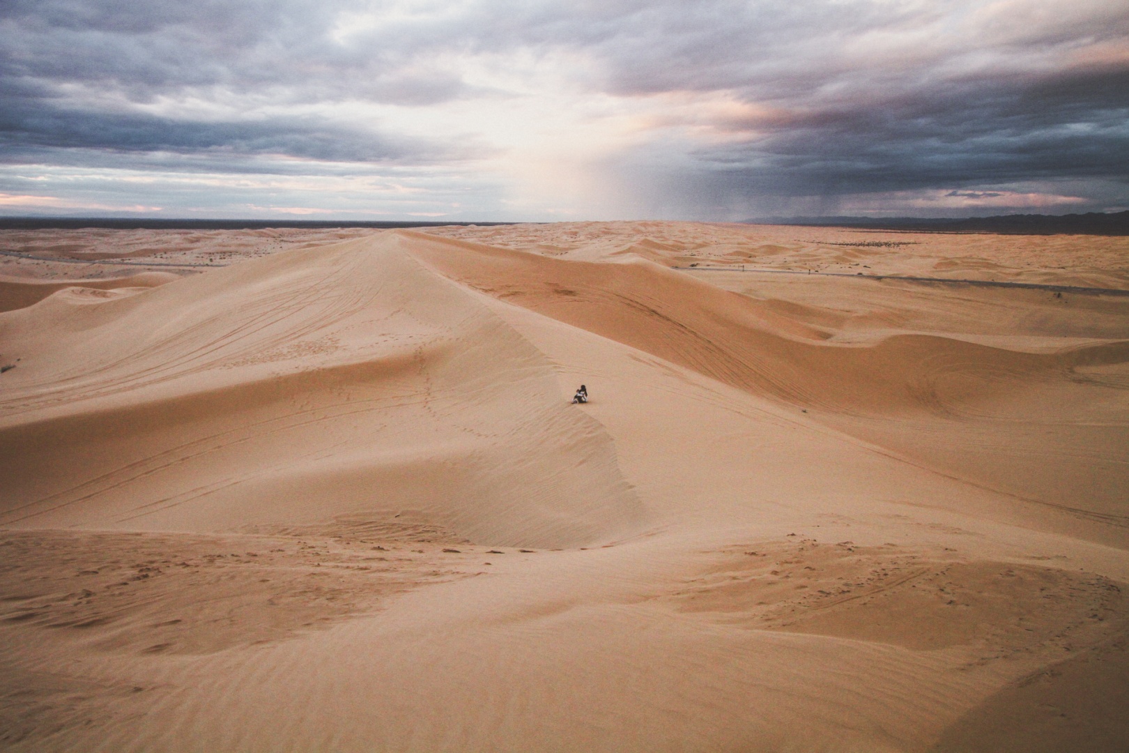 Eine Frau sitzt auf einer Sanddüne in der Wüste.